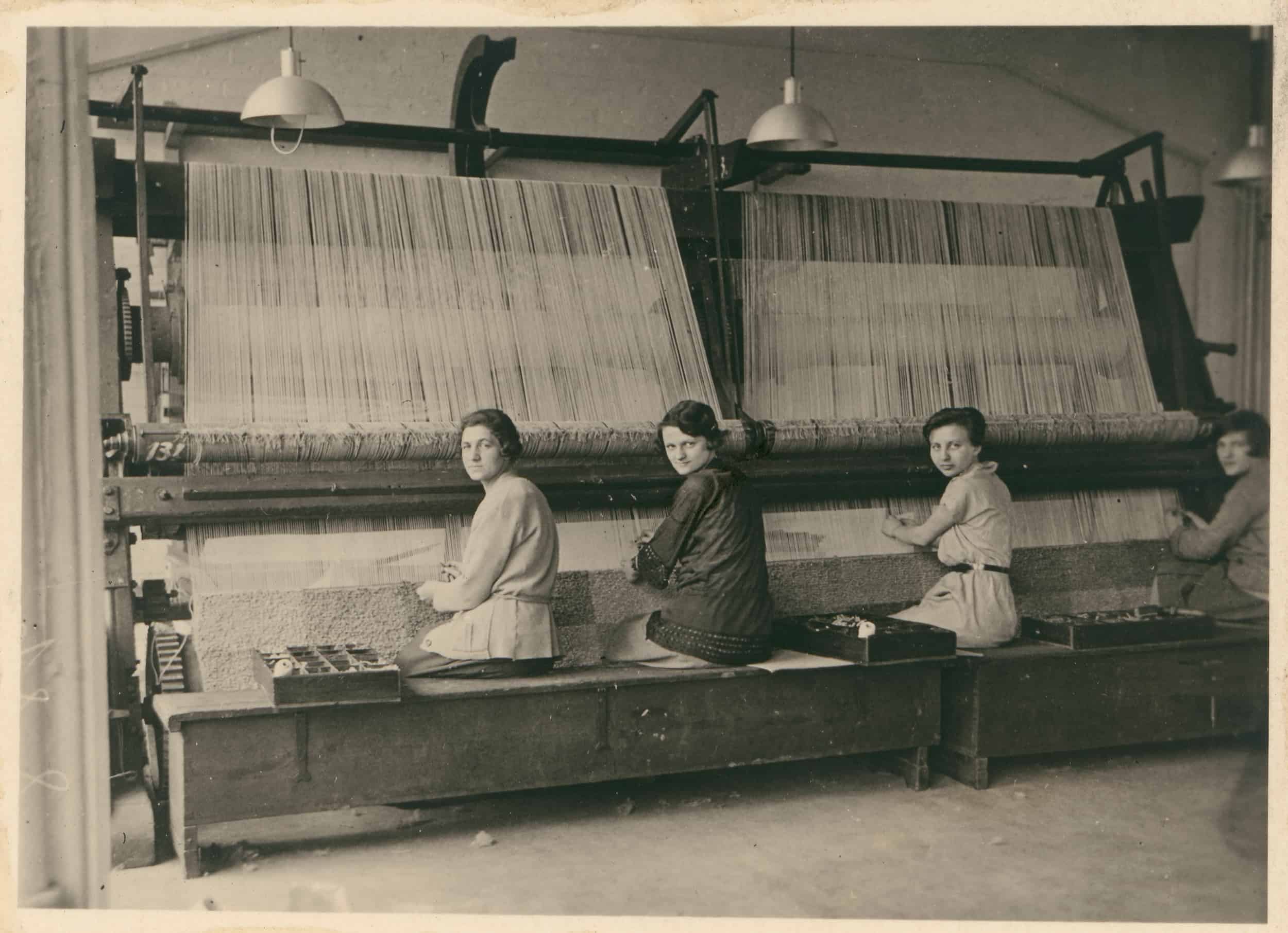 Archivbild. Vier Bauhaus-Studentinnen sitzen vor einem großen Webstuhl.