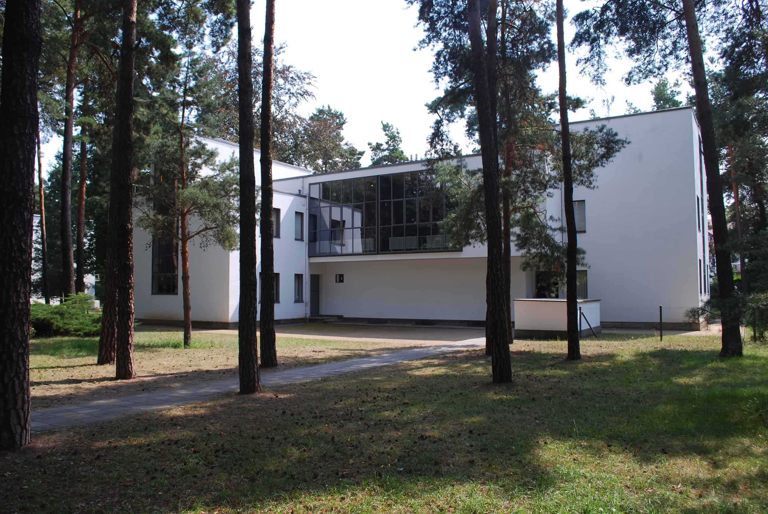 Das zweistöckige weiße Meisterhaus von Klee und Kandinsky ist umgeben von hohen Bäumen.