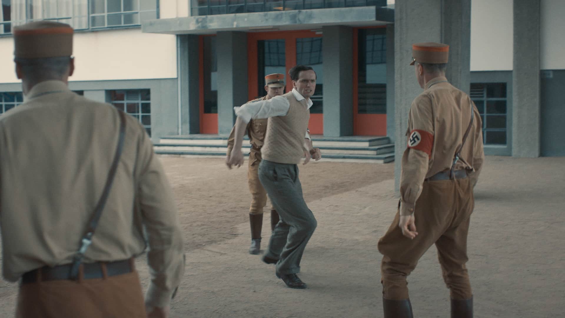 Filmszene. Josef Albers rennt wutentbrannt auf einen Nazi zu. Er ist von anderen Nazis umzingelt.